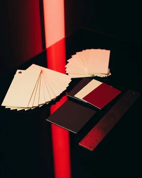 Paper swatches, three colour chips and a steel ruler on black glass.