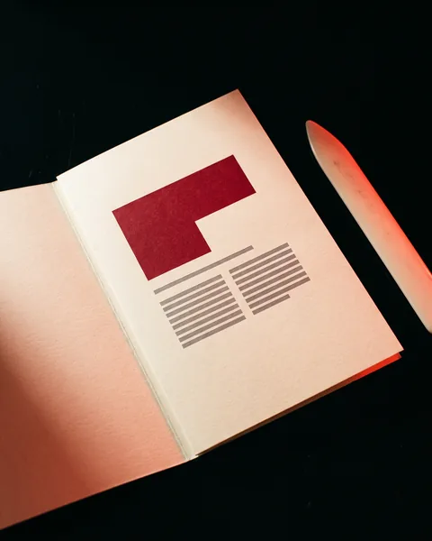 An open printed folder — a red block and grey placeholder lines on cream stock.